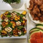 Fresh peach and burrata salad topped with basil, arugula, and drizzled with balsamic glaze.