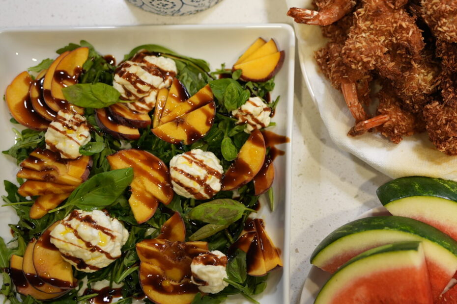 Fresh peach and burrata salad topped with basil, arugula, and drizzled with balsamic glaze.