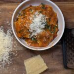 Bowl of creamy red sauce pasta topped with fresh herbs and served in a rustic dish.