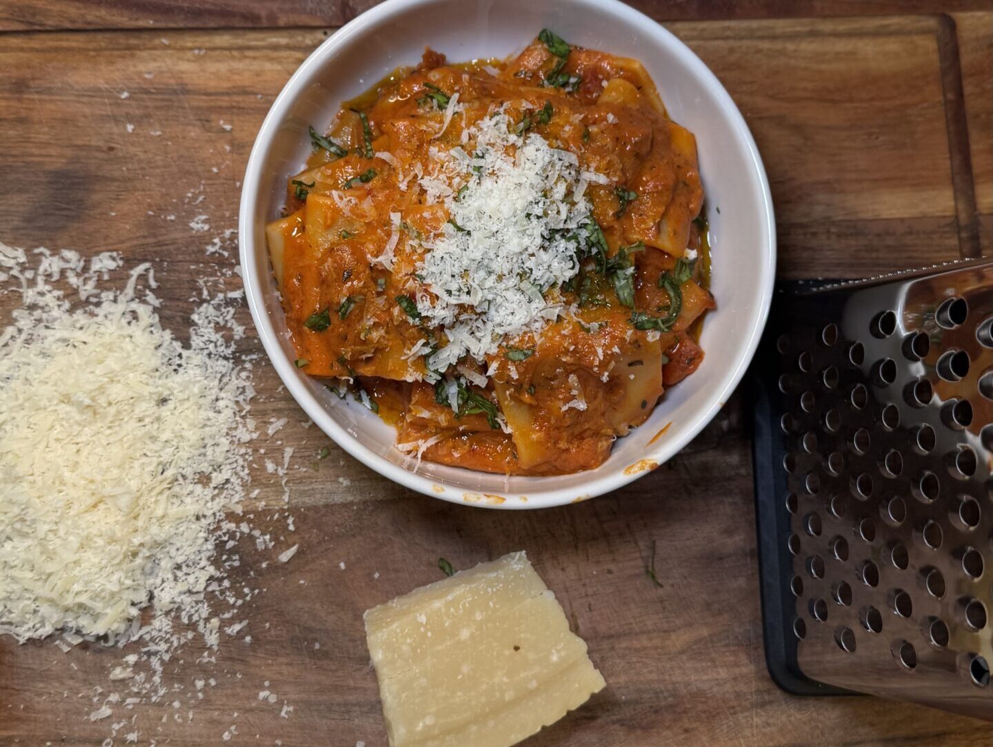 Bowl of creamy red sauce pasta topped with fresh herbs and served in a rustic dish.
