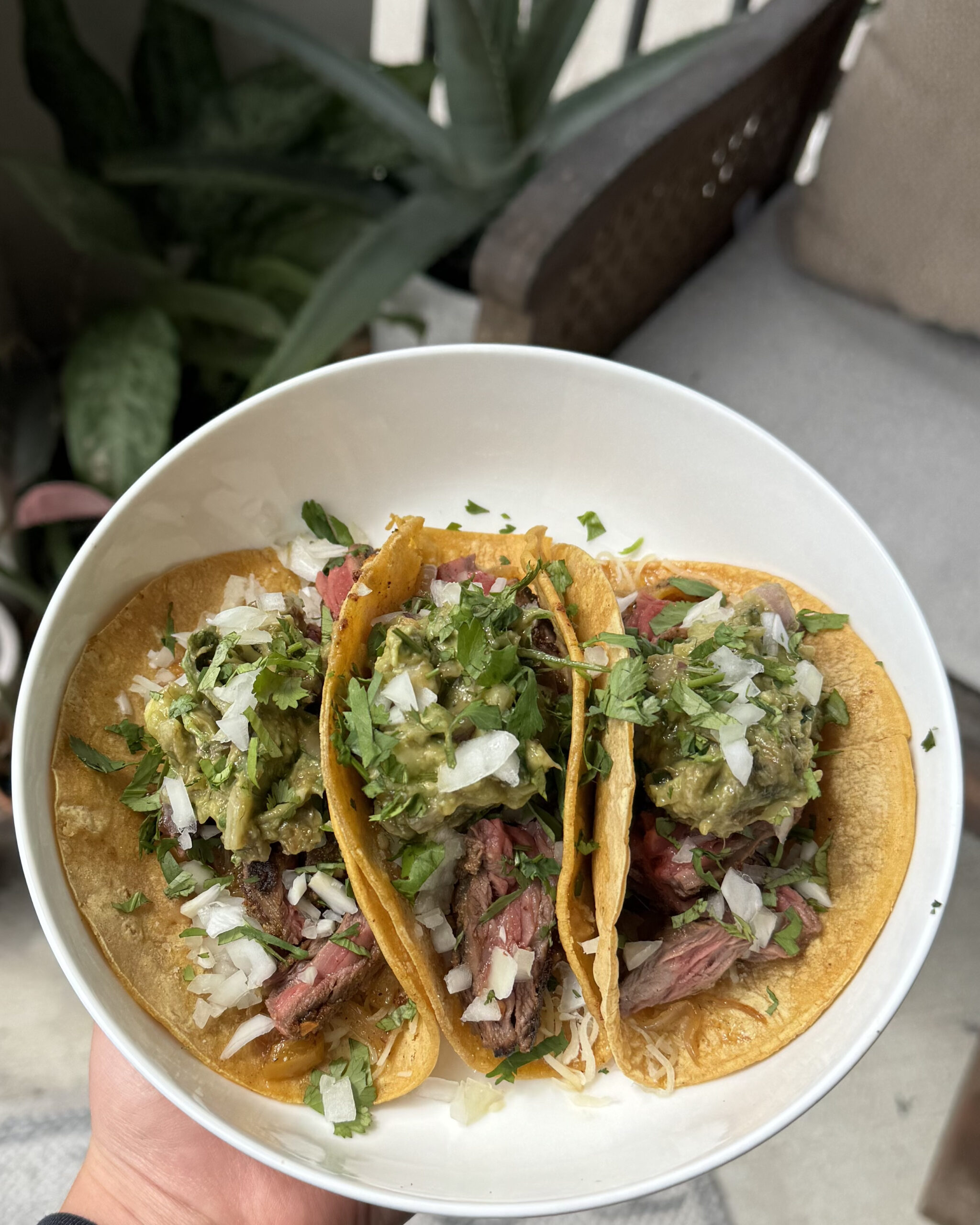 Authentic Mexican street-style carne asada tacos topped with cilantro, onion, and salsa on a rustic wooden board